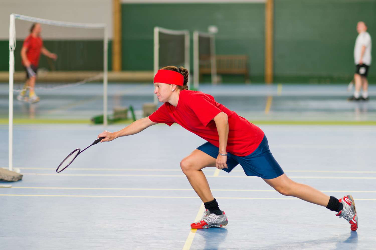 a female badminton player aims for a shuttlecock near the net