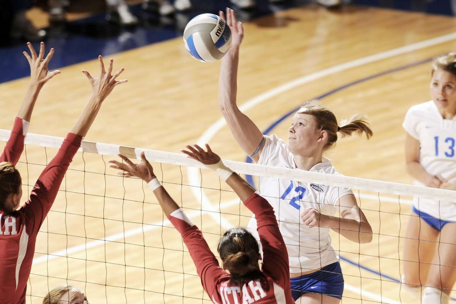 a female volleyball player hits the volleyball near the net